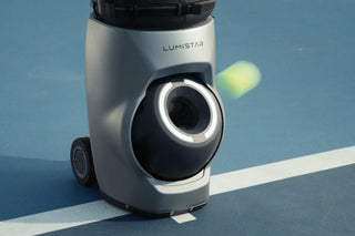Tennis ball leaving the launcher of a Lumistar TERO Pro on an outdoor court