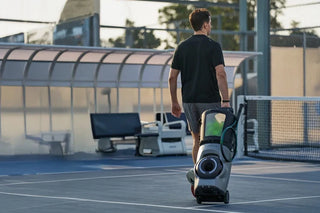 Player rolling a Lumistar TERO Pro tennis training robot onto the court