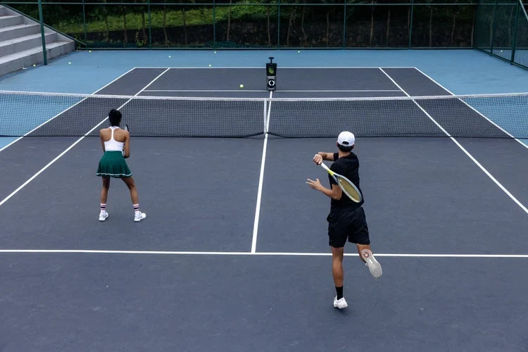 Two tennis players practicing on court with a Lumistar TERO Pro across the net