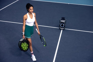 Tennis player carrying a ball bag beside a Lumistar TERO Pro tennis robot.