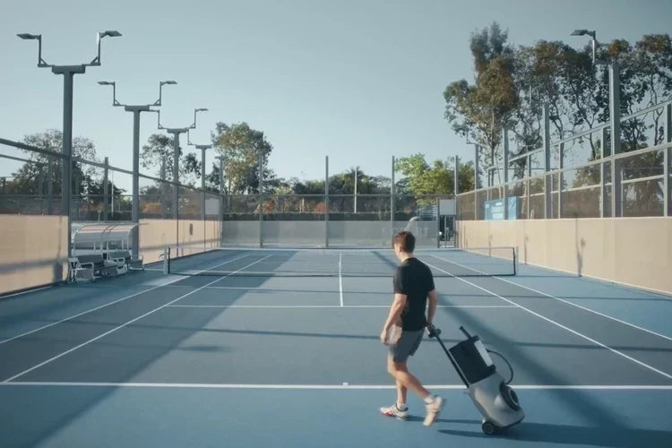 Player bringing a Lumistar TERO Pro tennis training robot onto an outdoor court