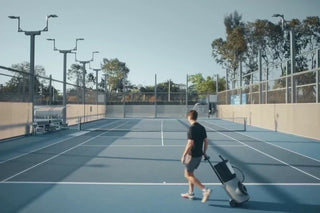 Player bringing a Lumistar TERO Pro tennis training robot onto an outdoor court