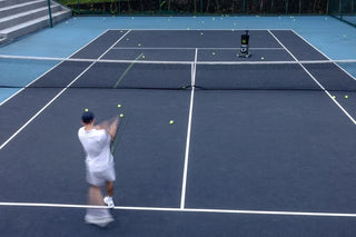 Beginner practicing a forehand across the net from a Lumistar TERO Pro tennis training robot